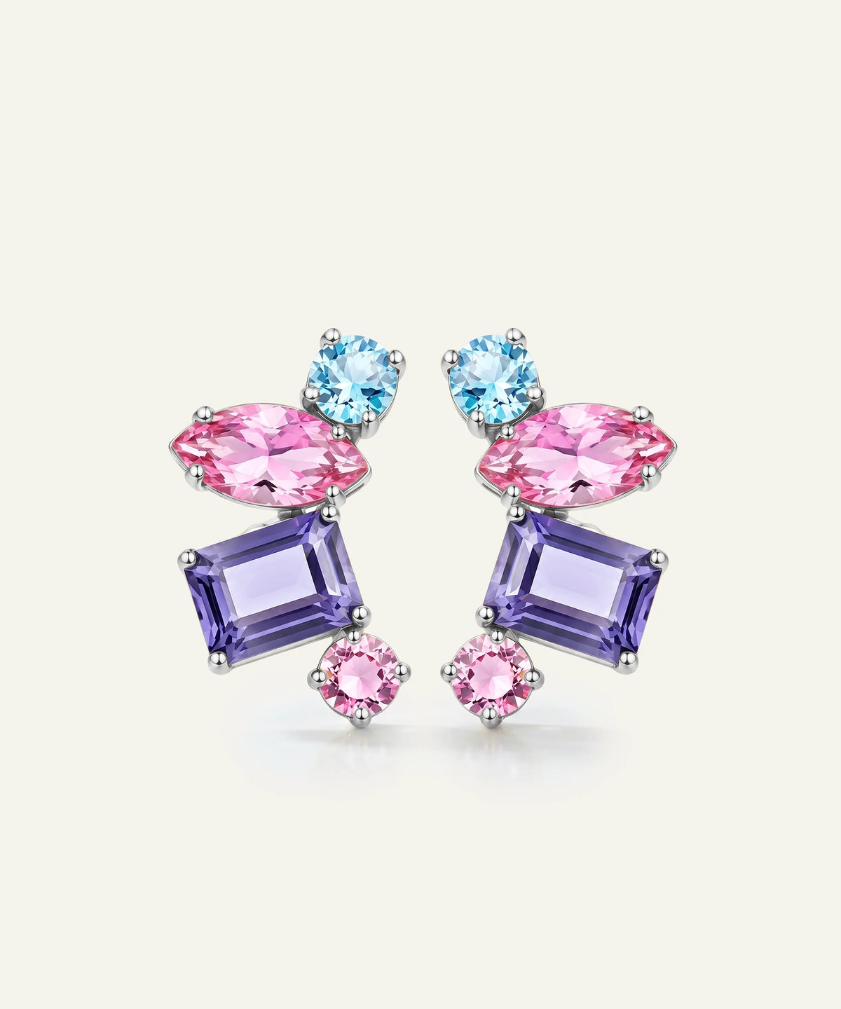 A pair of colorful gemstone stud earrings featuring light blue round crystals, pink marquise-shaped crystals, and lavender rectangular crystals set in silver-toned metal, displayed on a light cream background.