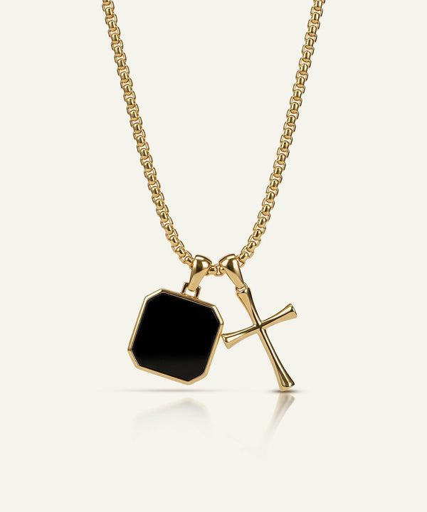 Gold necklace with a black pendant on a white background