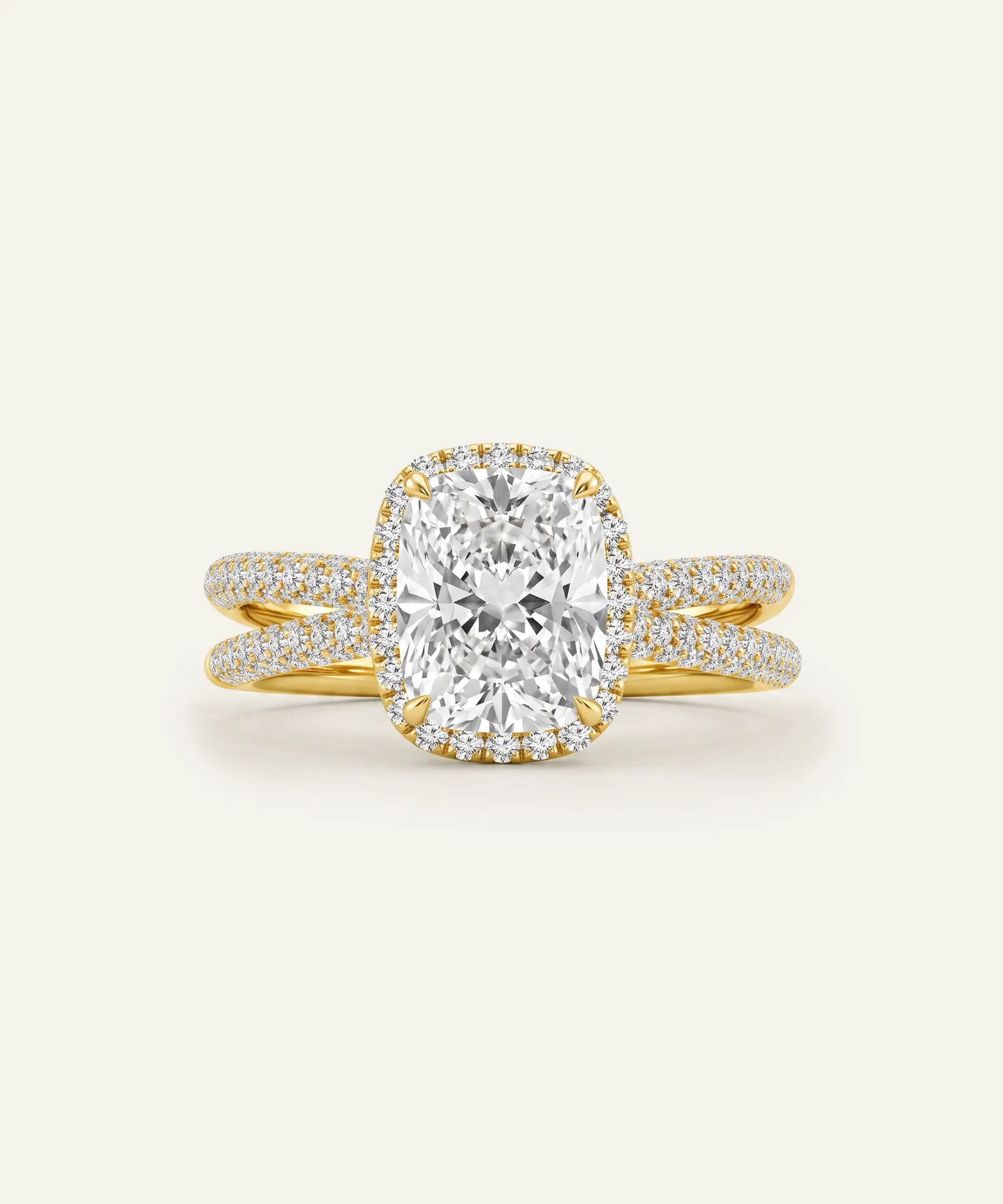 A yellow gold engagement ring featuring a large cushion-cut diamond center stone surrounded by a halo of small diamonds, with a split shank also paved with diamonds, set against a solid off-white background.