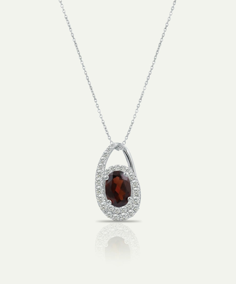 Silver pendant with a red gemstone on a white background