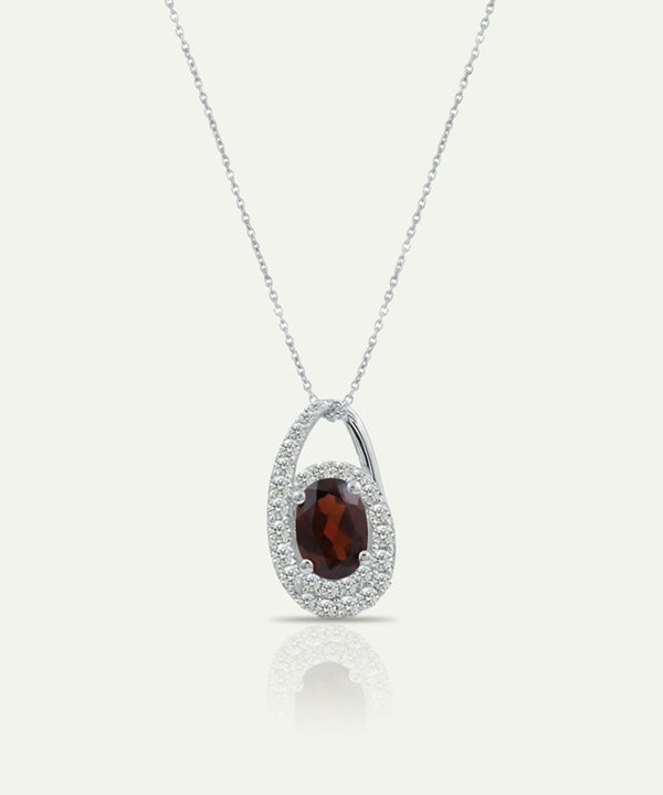 Silver pendant with a red gemstone on a white background