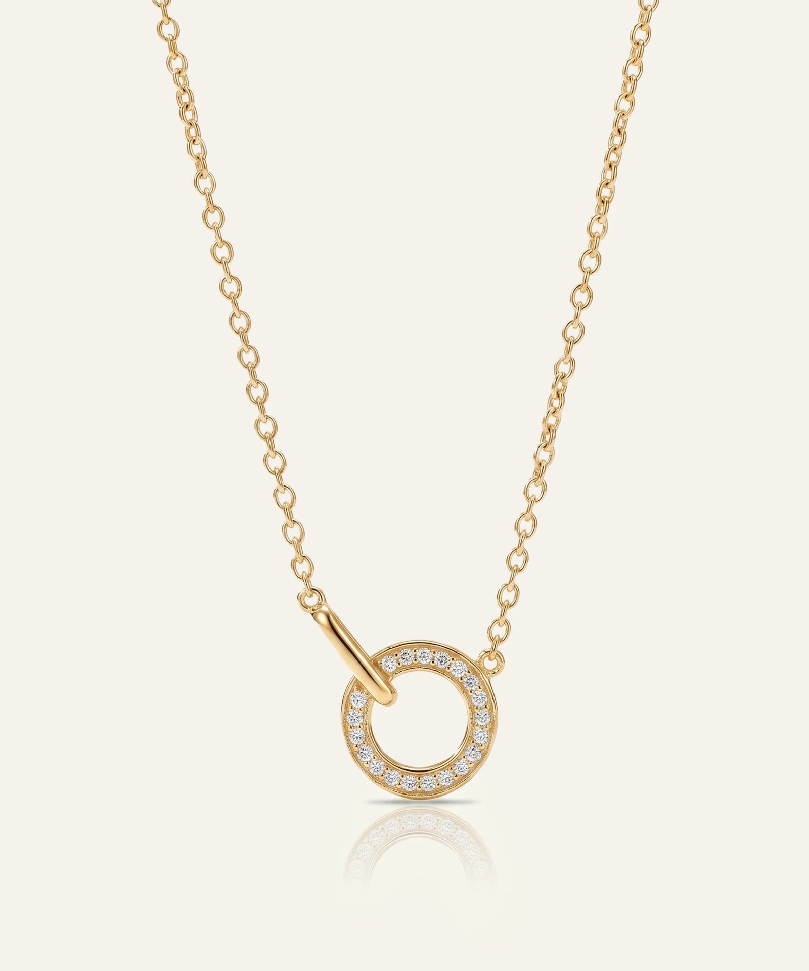 Gold necklace with a circular pendant on a light beige background