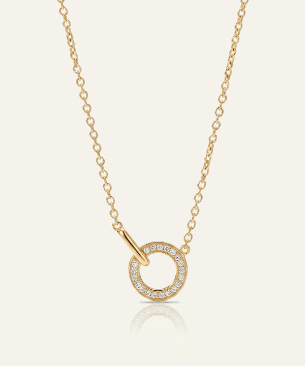 Gold necklace with a circular pendant on a light beige background