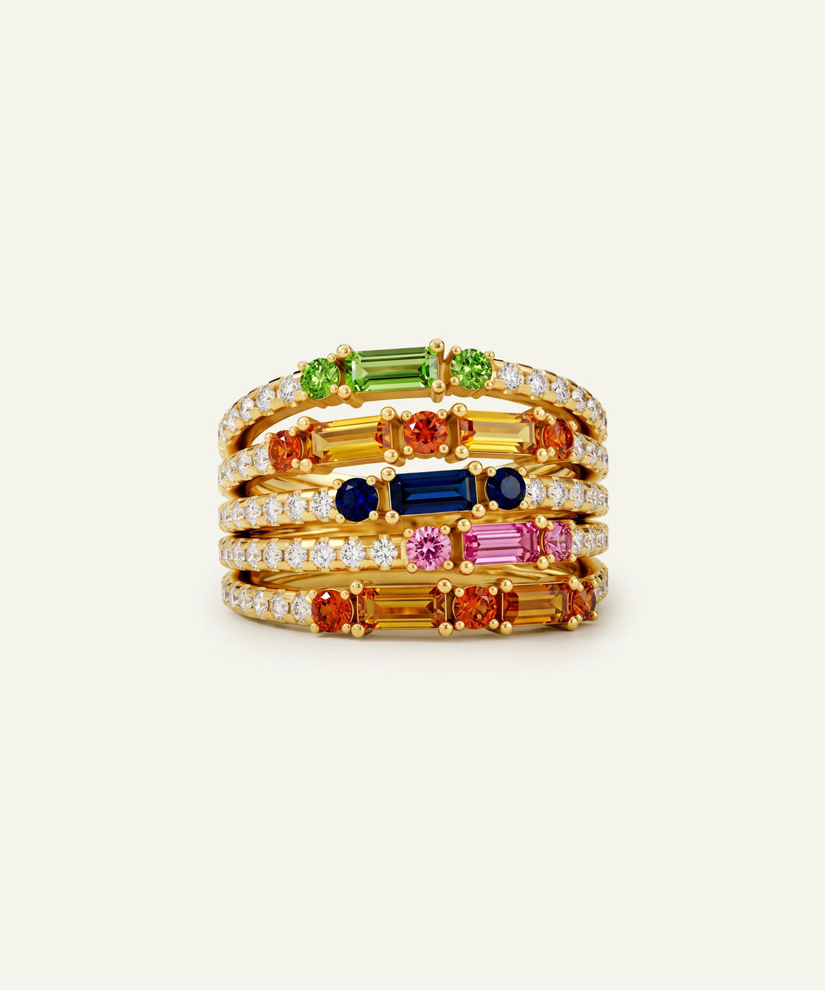 A stack of four gold rings featuring colorful gemstones, including green, orange, blue, pink, and baguette-cut stones, set against a plain off-white background.