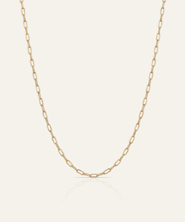 Gold chain necklace on a light beige background