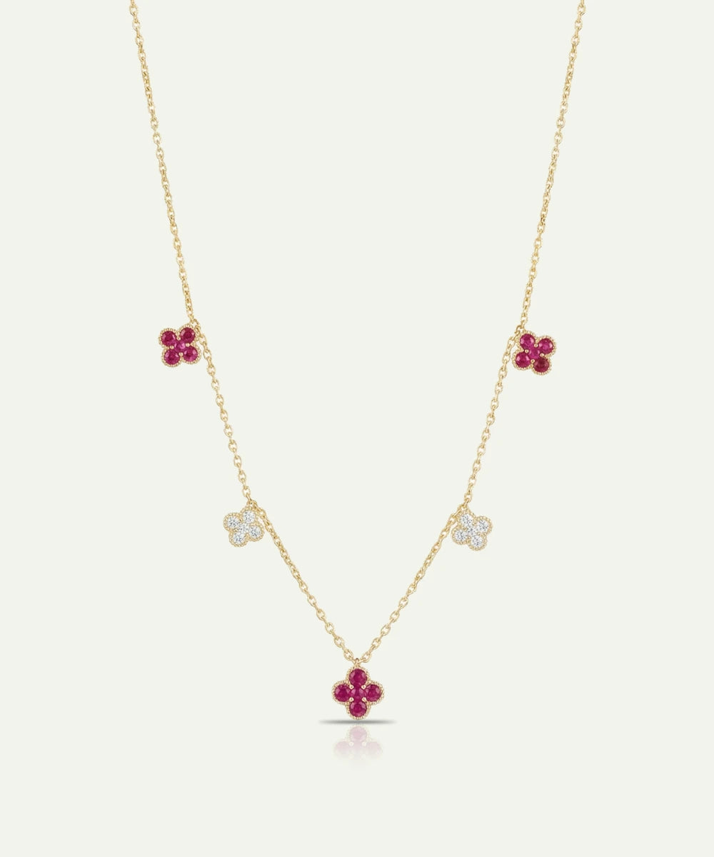 Gold necklace with floral pendants featuring red stones on a white background
