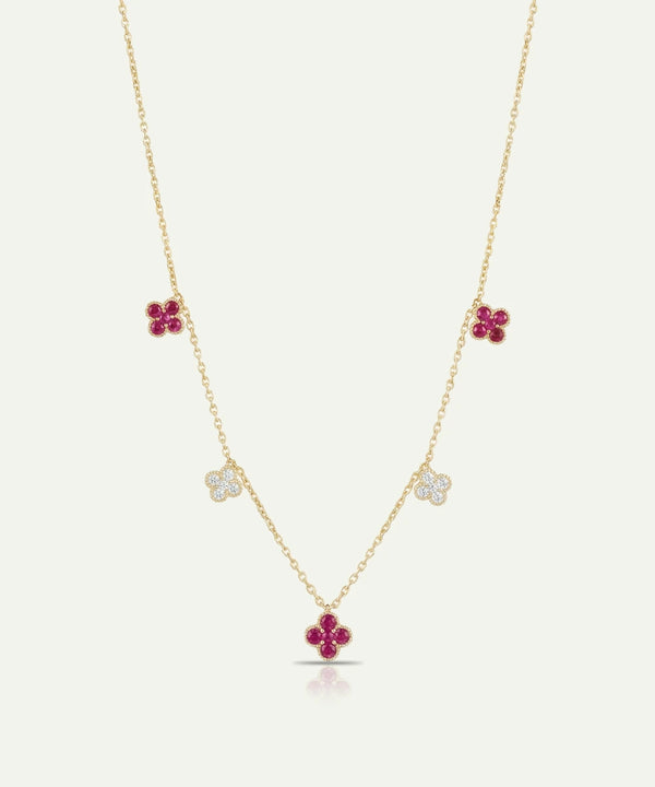 Gold necklace with floral pendants featuring red stones on a white background