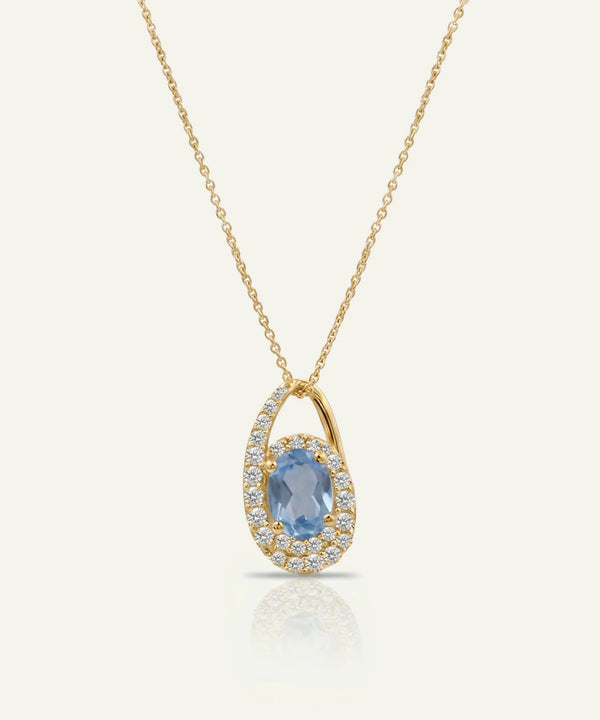 Gold necklace with a blue gemstone pendant on a white background