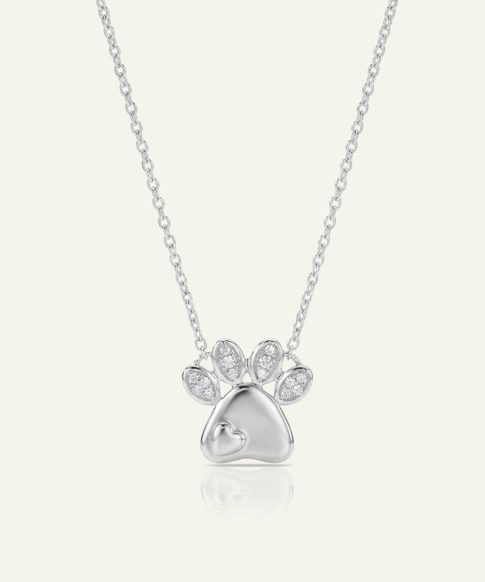Silver paw print necklace with clear stones on a light gray background