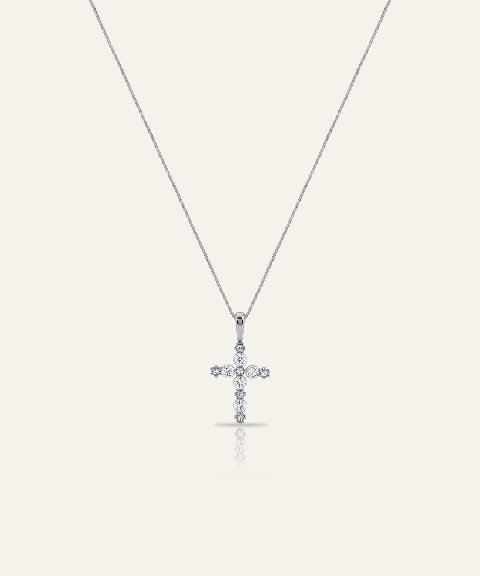 Diamond cross pendant on a thin chain against a light gray background