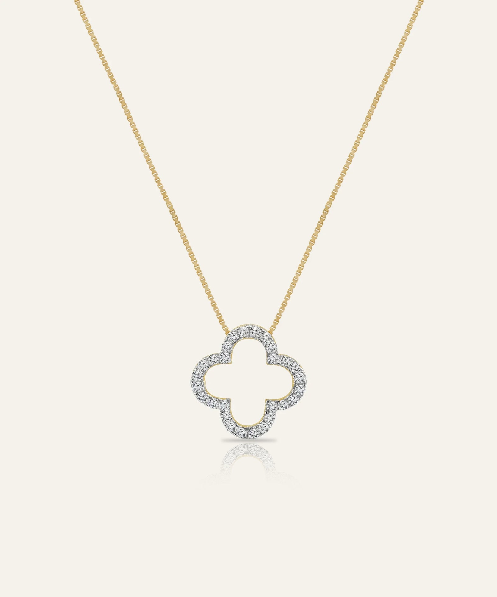 Gold necklace with a clover-shaped pendant on a light gray background