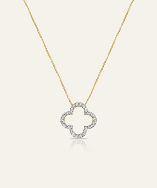 Gold necklace with a clover-shaped pendant on a light gray background