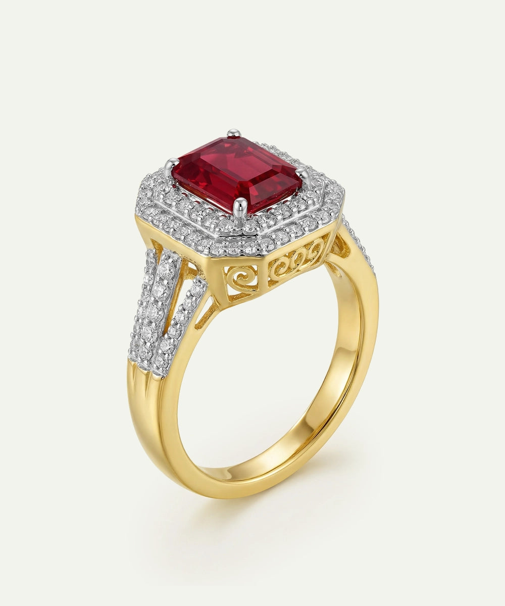 Gold ring with a red gemstone and diamond accents on a white background