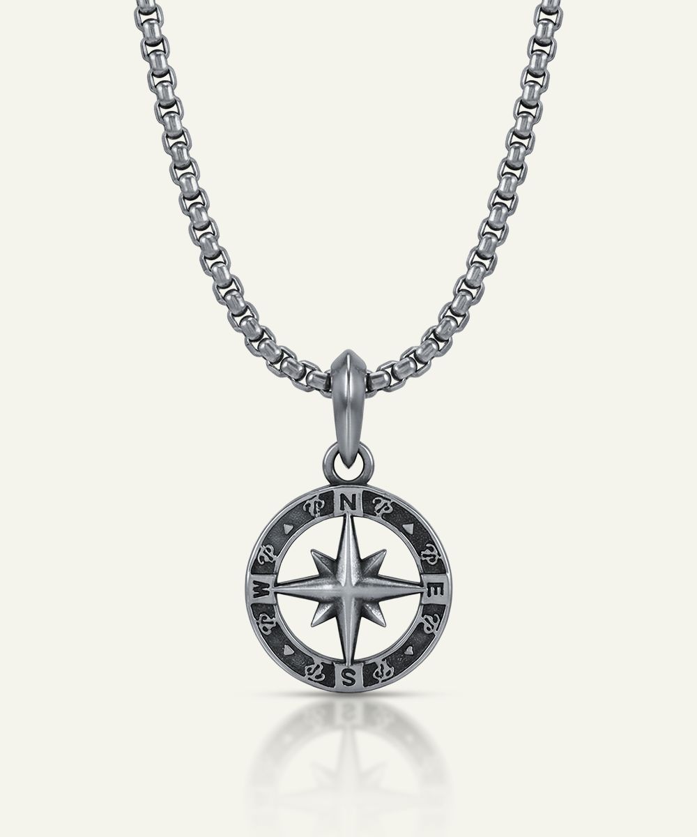 Silver compass necklace on a white background