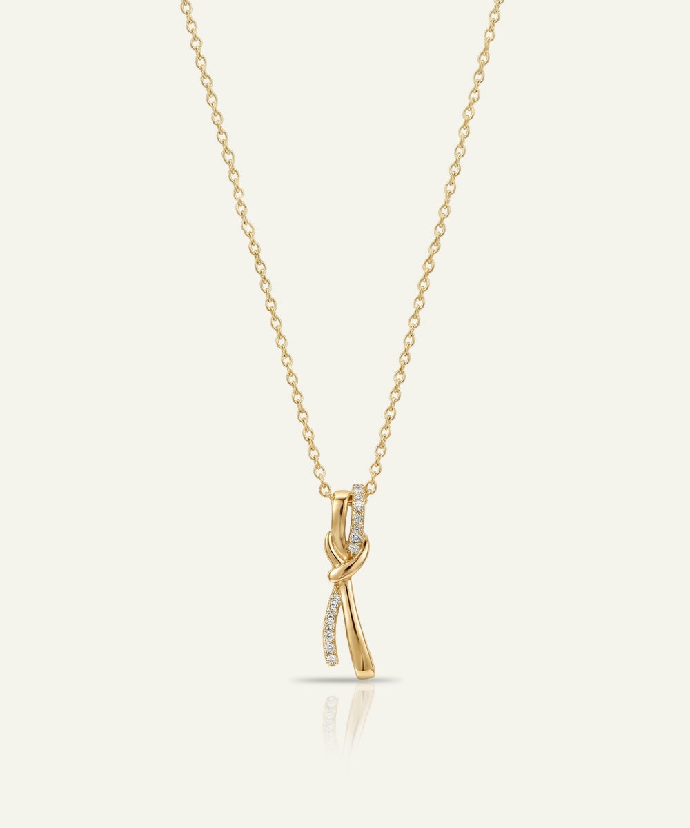 Gold necklace with a delicate pendant on a light beige background