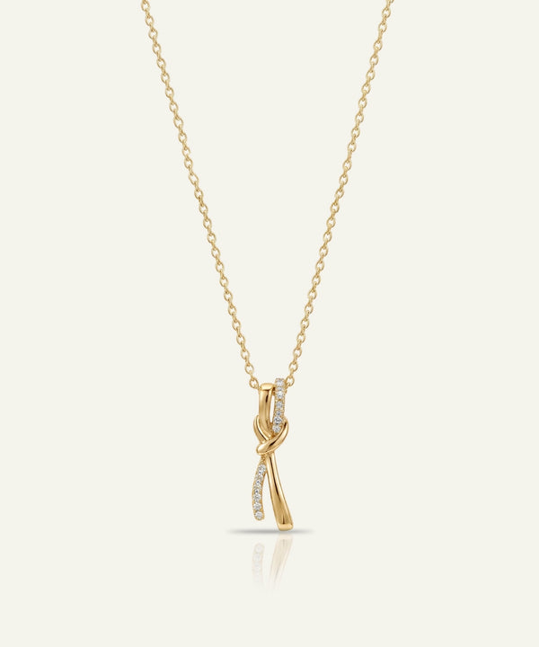 Gold necklace with a delicate pendant on a light beige background