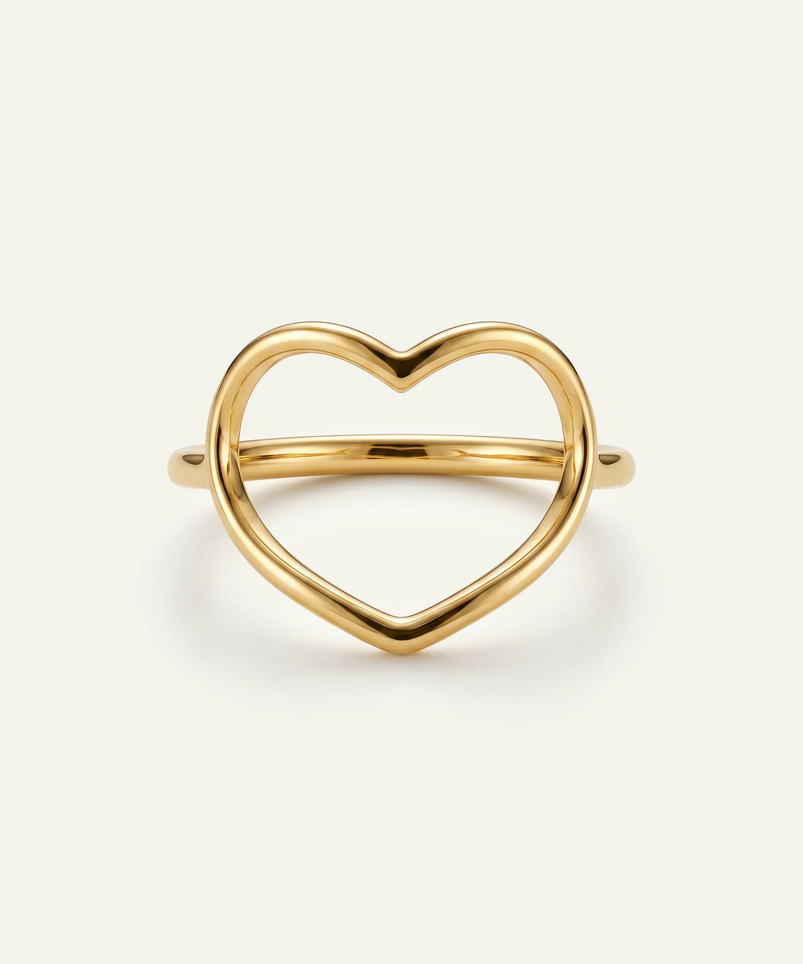 Gold heart-shaped ring on a light beige background