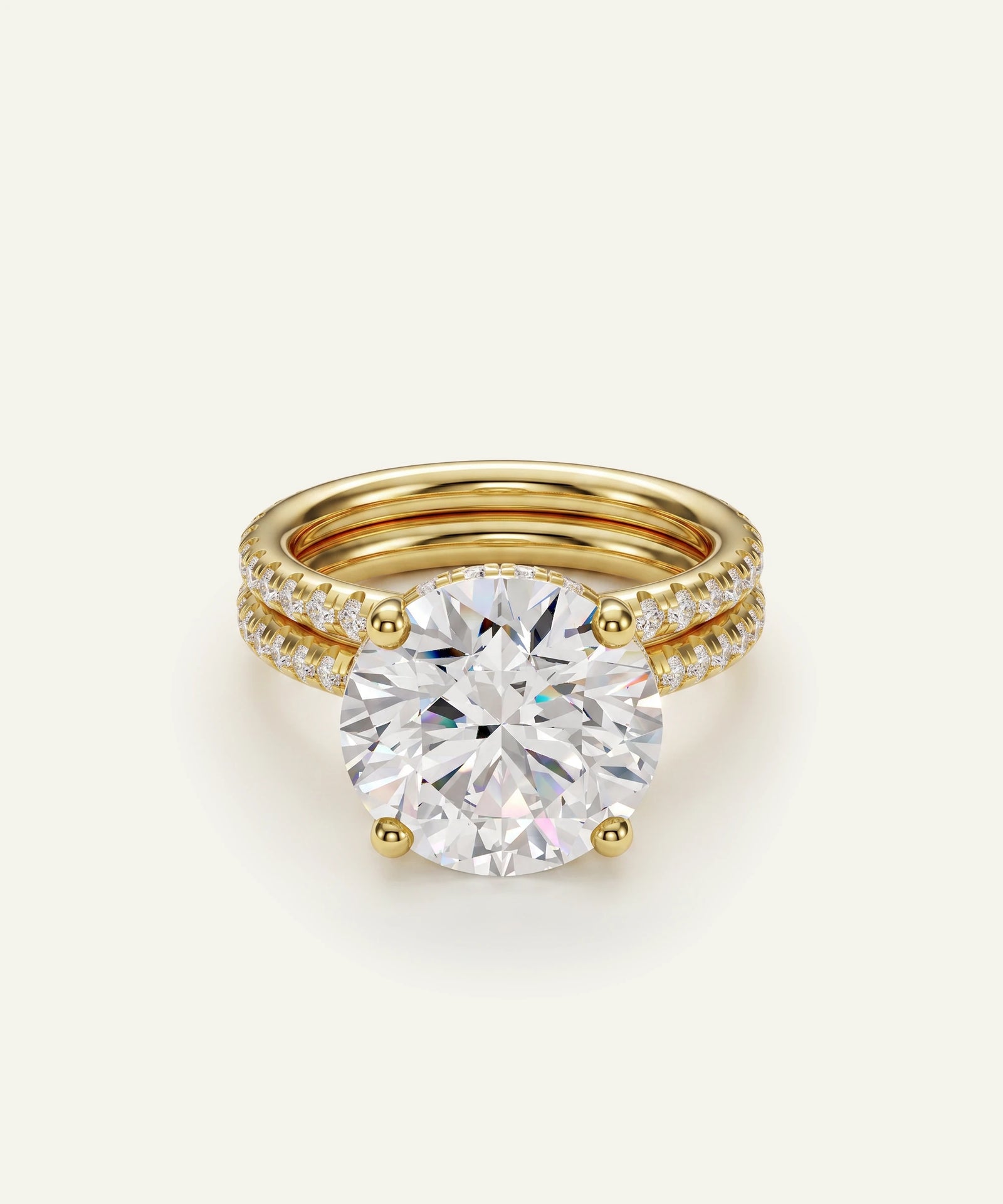 A gold engagement ring with a large round brilliant-cut center stone and a double-row pavé band, shown on a clean off-white background.