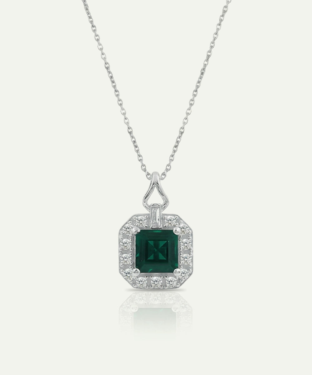 Silver necklace with a green gemstone pendant on a white background