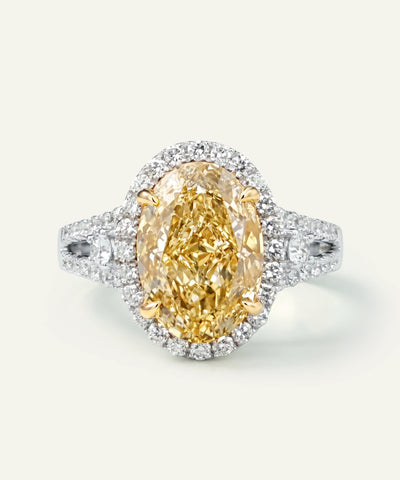 Ring with a yellow diamond and white diamond halo on a light gray background