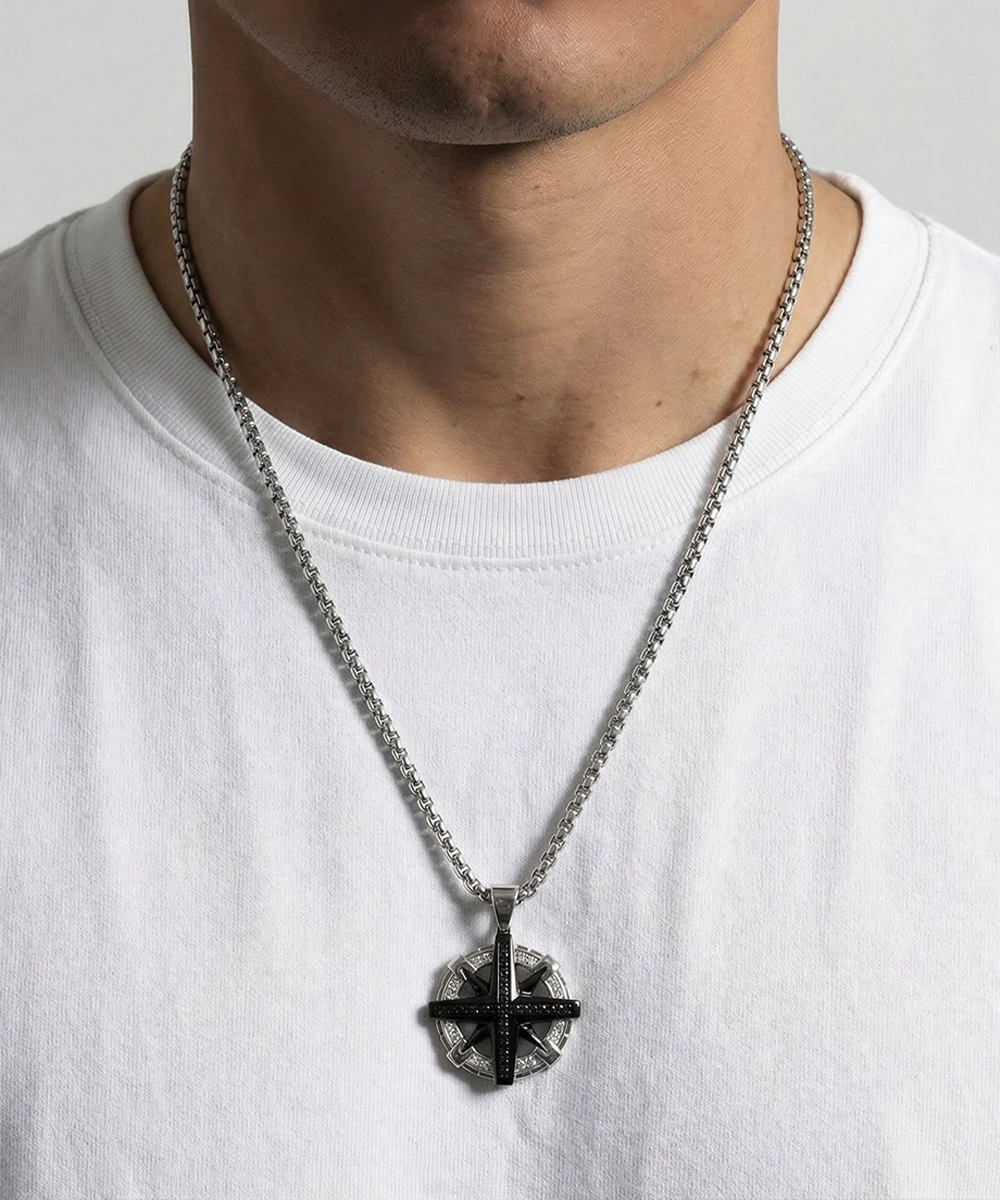 Person wearing a silver necklace with a pendant on a plain background