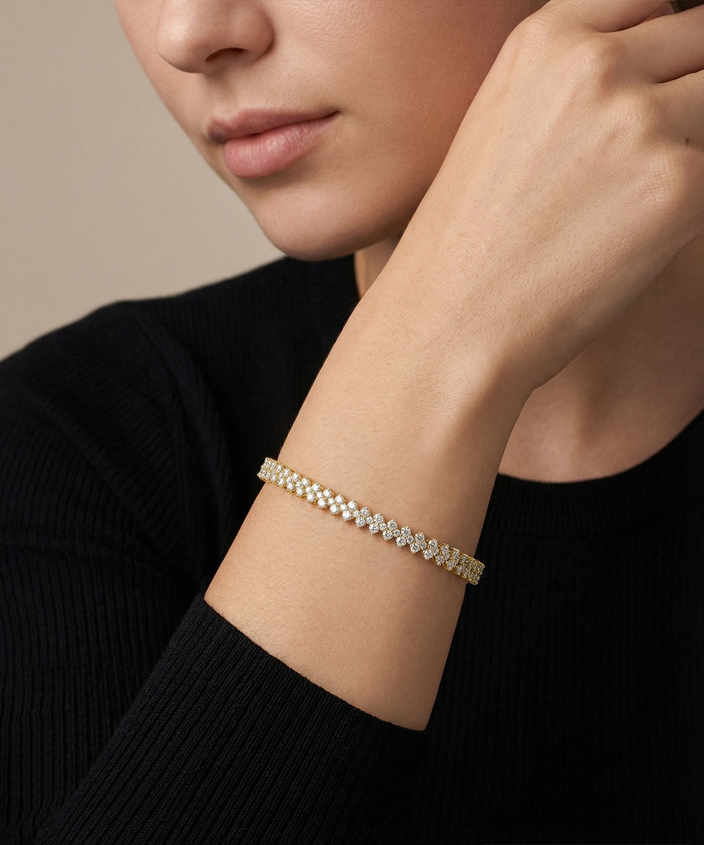 Close-up of a person wearing a gold bracelet on a neutral background