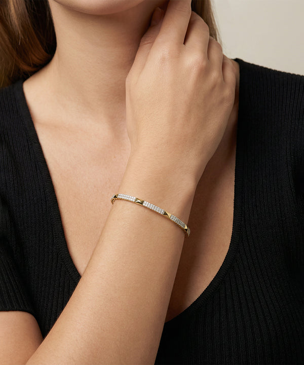 Gold bracelet on a person's wrist with a neutral background