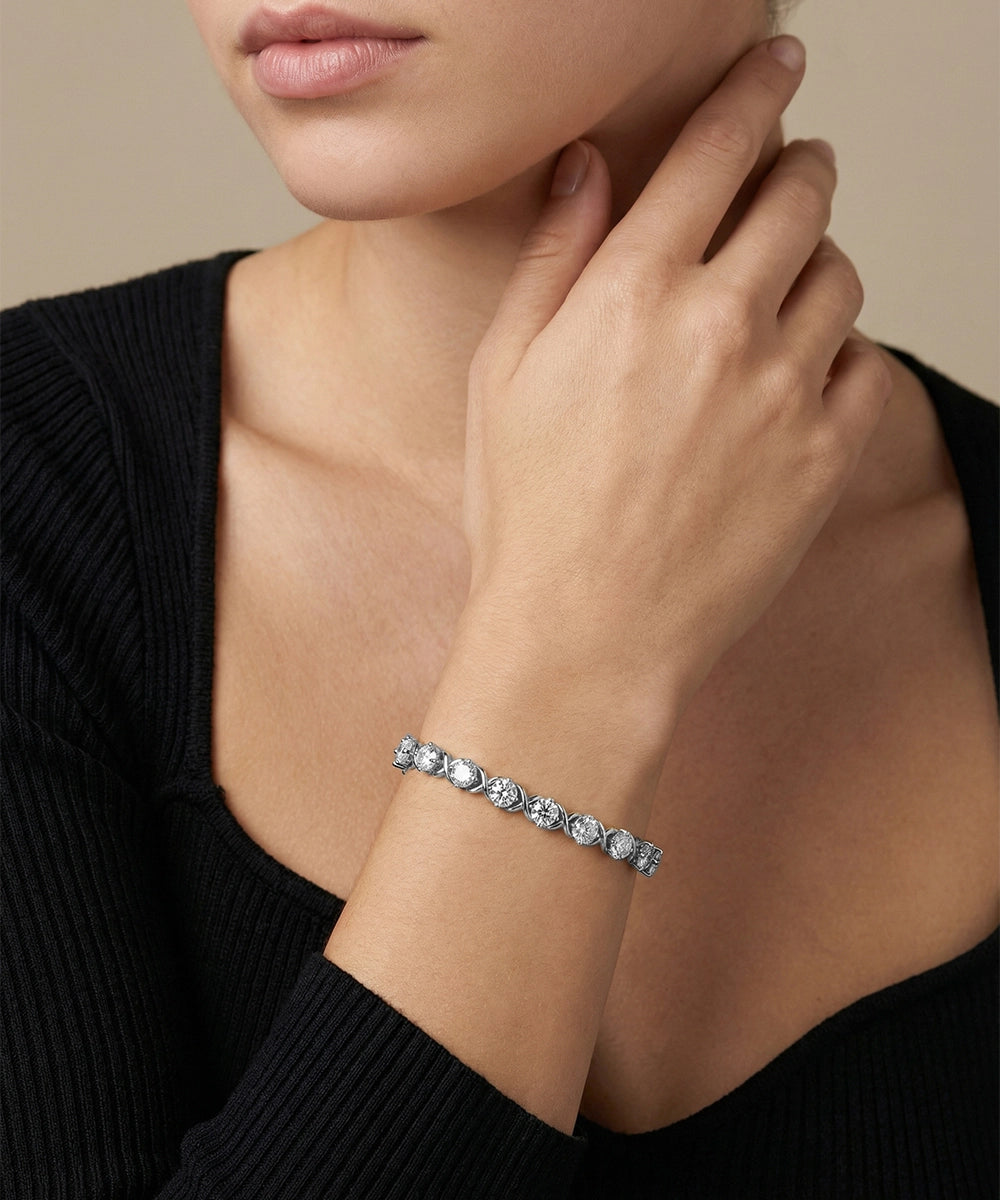 Gold bracelet with gemstones on a person's wrist against a neutral background