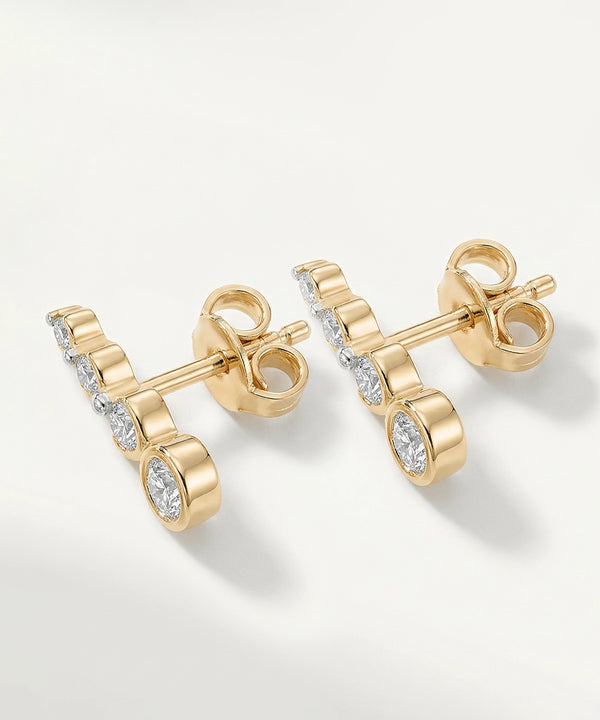 Gold earrings with clear gemstones on a light gray background