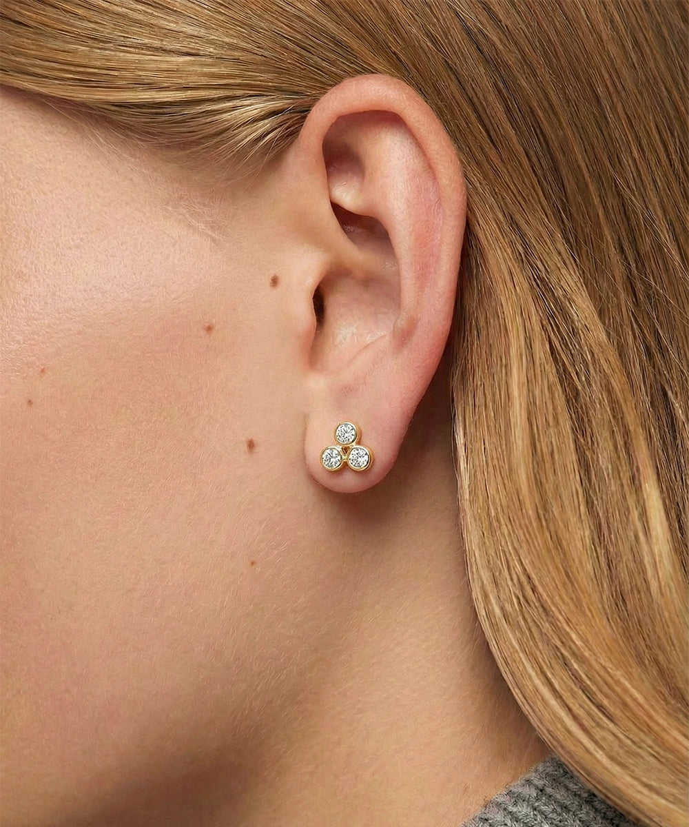 Close-up of an ear wearing a set of earrings with a neutral background