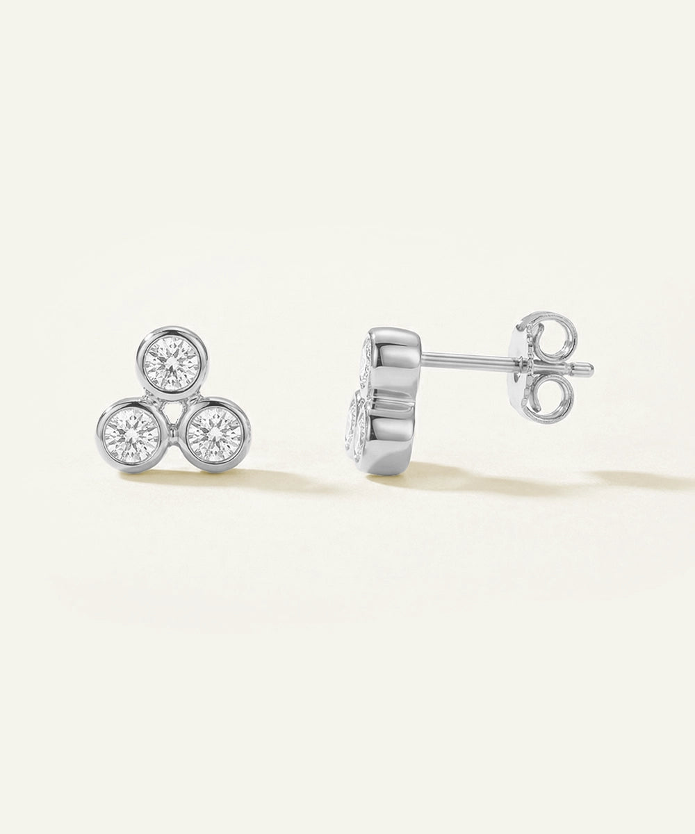 Pair of silver earrings with diamond-like stones on a light beige background