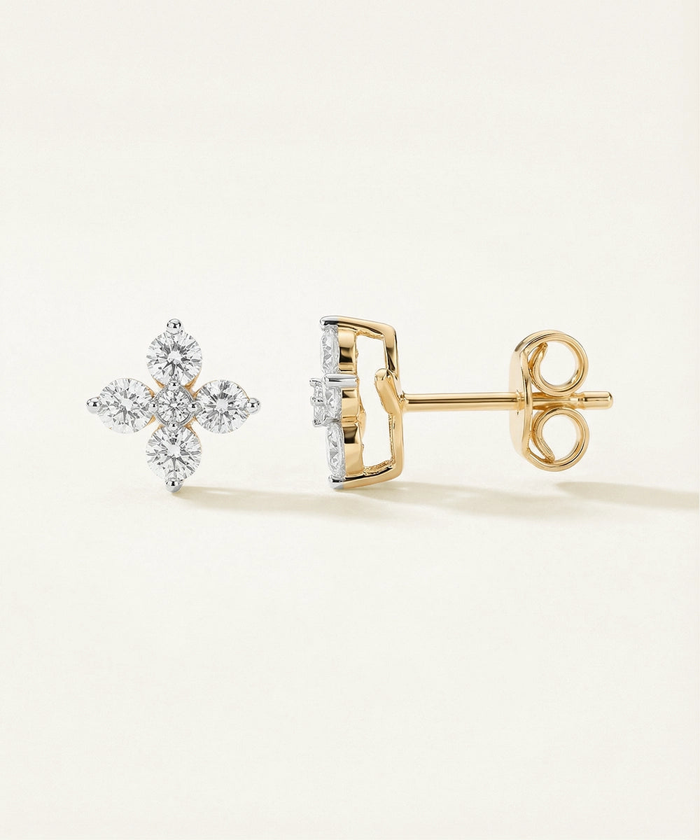 Gold and silver diamond earrings on a light beige background