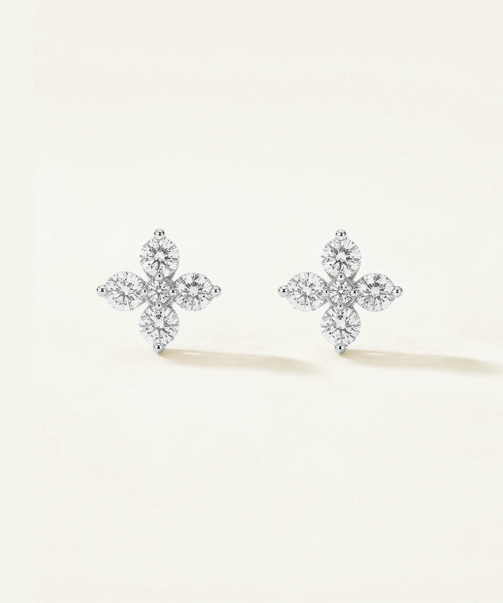 Pair of diamond cross earrings on a light beige background