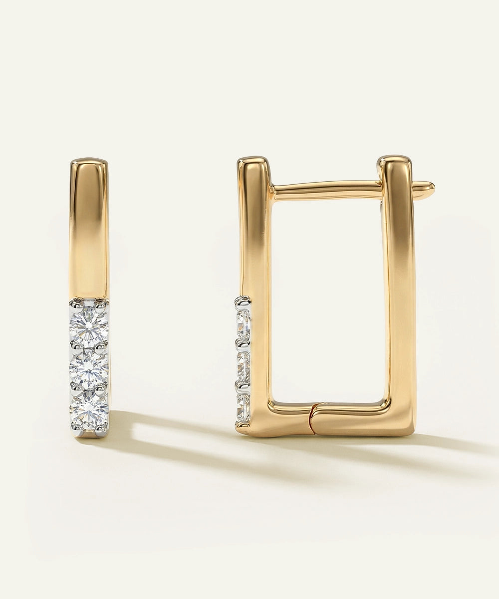 Gold hoop earrings with diamond accents on a light beige background