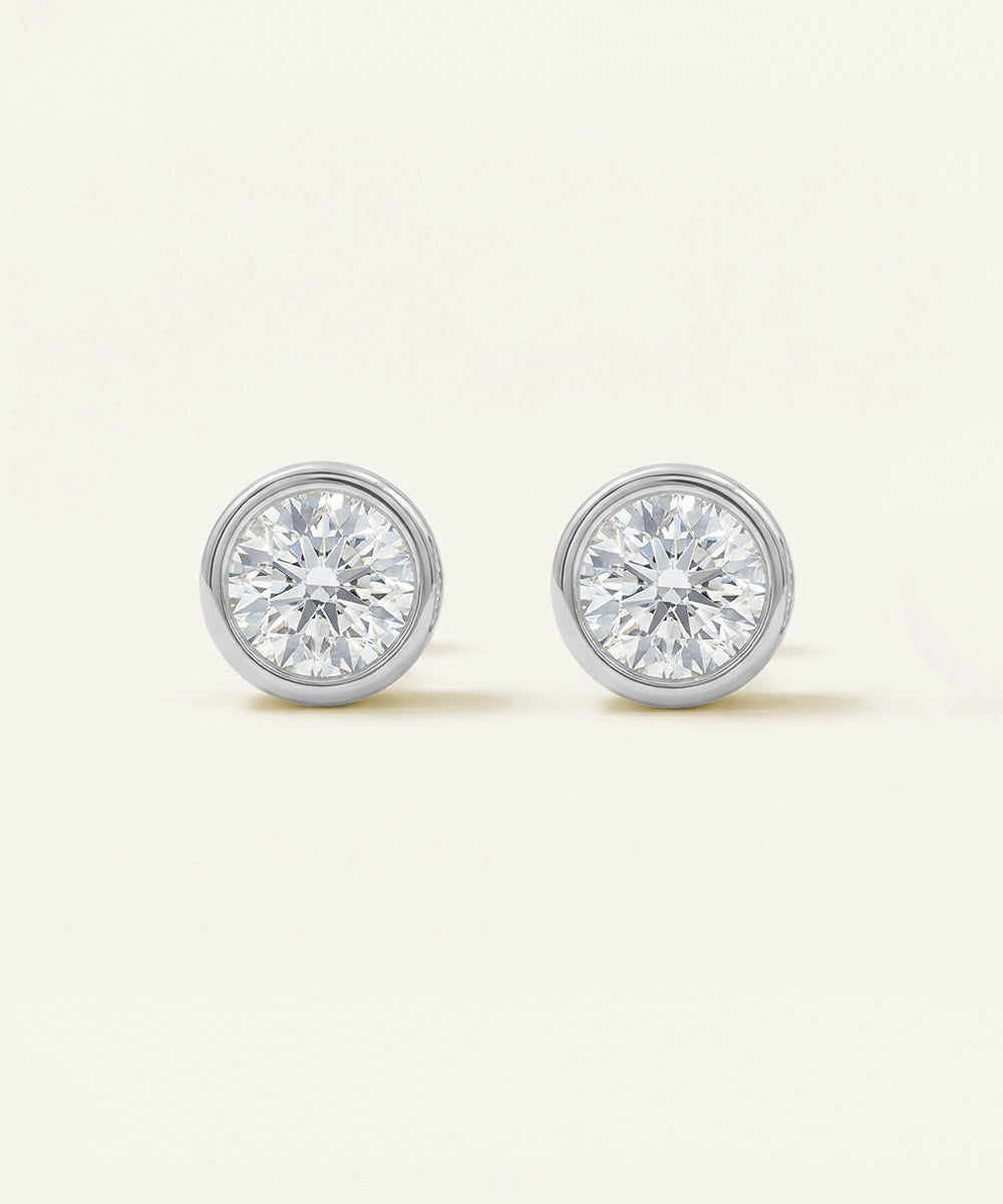 Pair of diamond stud earrings on a light beige background