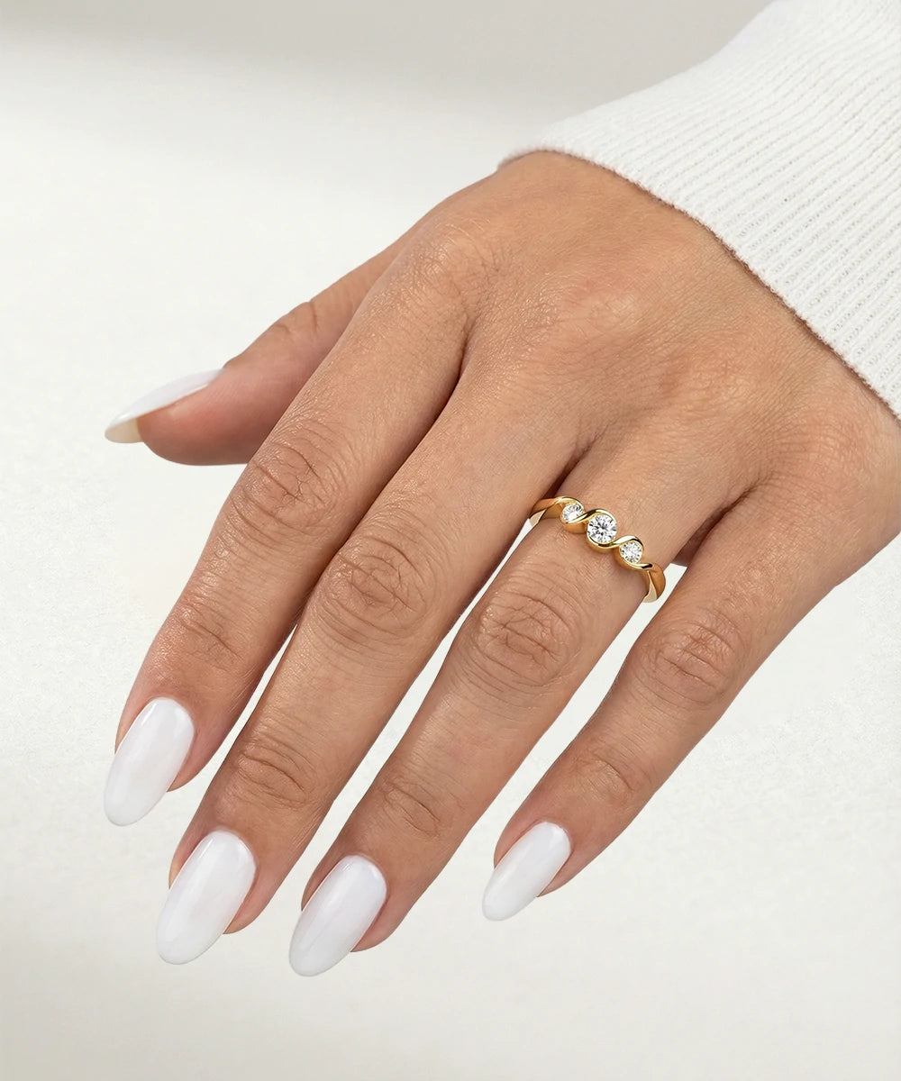 Hand wearing a gold ring with a diamond on a light background