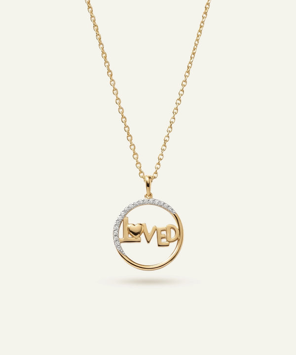 Gold necklace with a pendant that says 'LOVED' on a white background