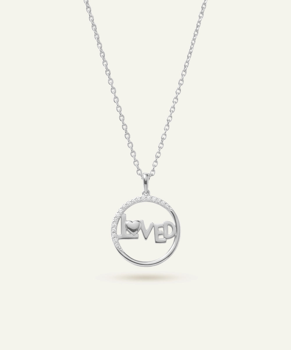 Silver necklace with a pendant that reads 'LOVED' on a white background