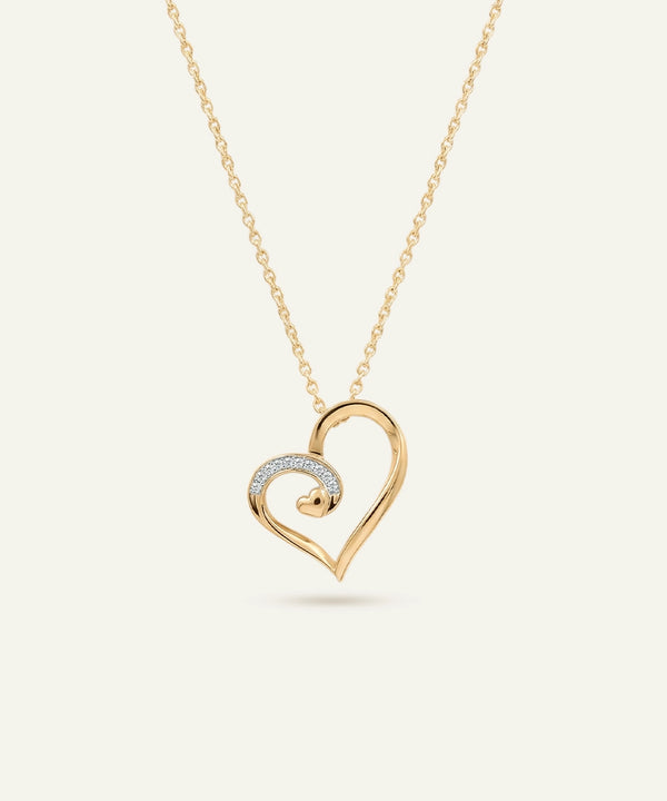 Gold heart-shaped necklace with a smaller heart pendant on a light beige background