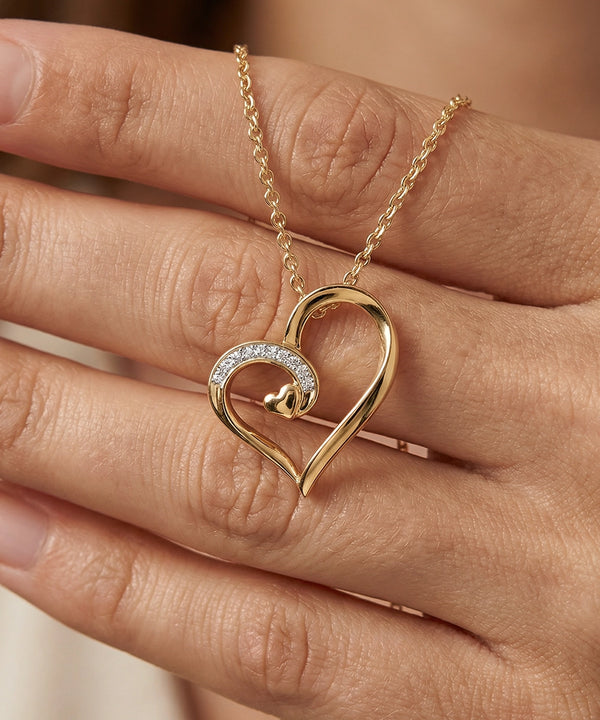 Gold heart-shaped necklace with diamond details on a hand