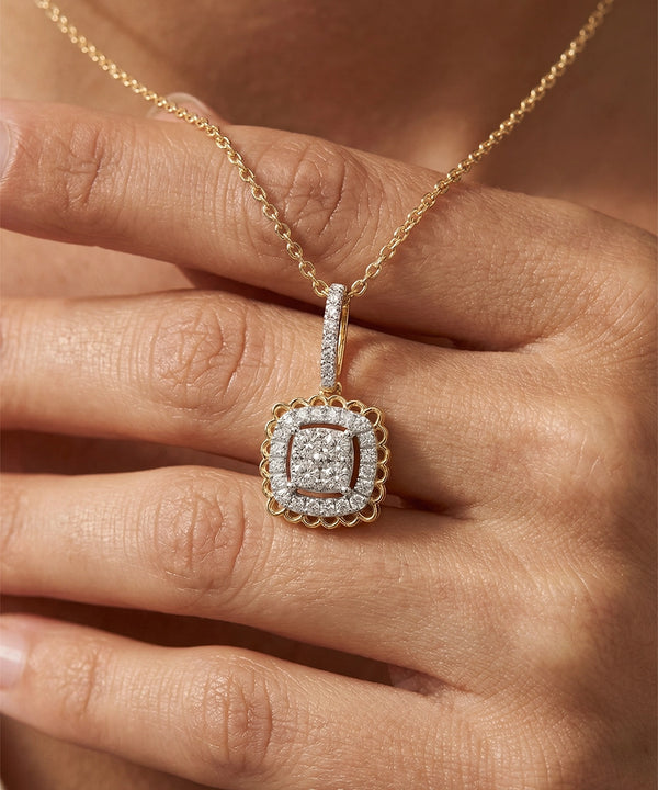 Gold necklace with a diamond pendant held by a hand