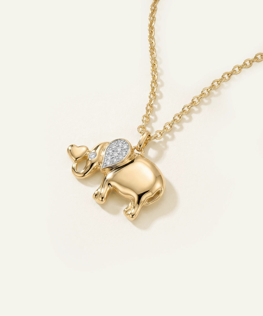 Gold elephant pendant necklace on a light beige background