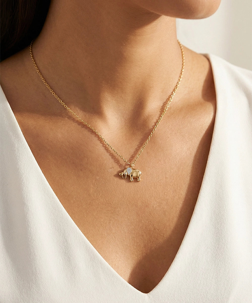 Gold necklace with a small pendant worn by a person in a white top.