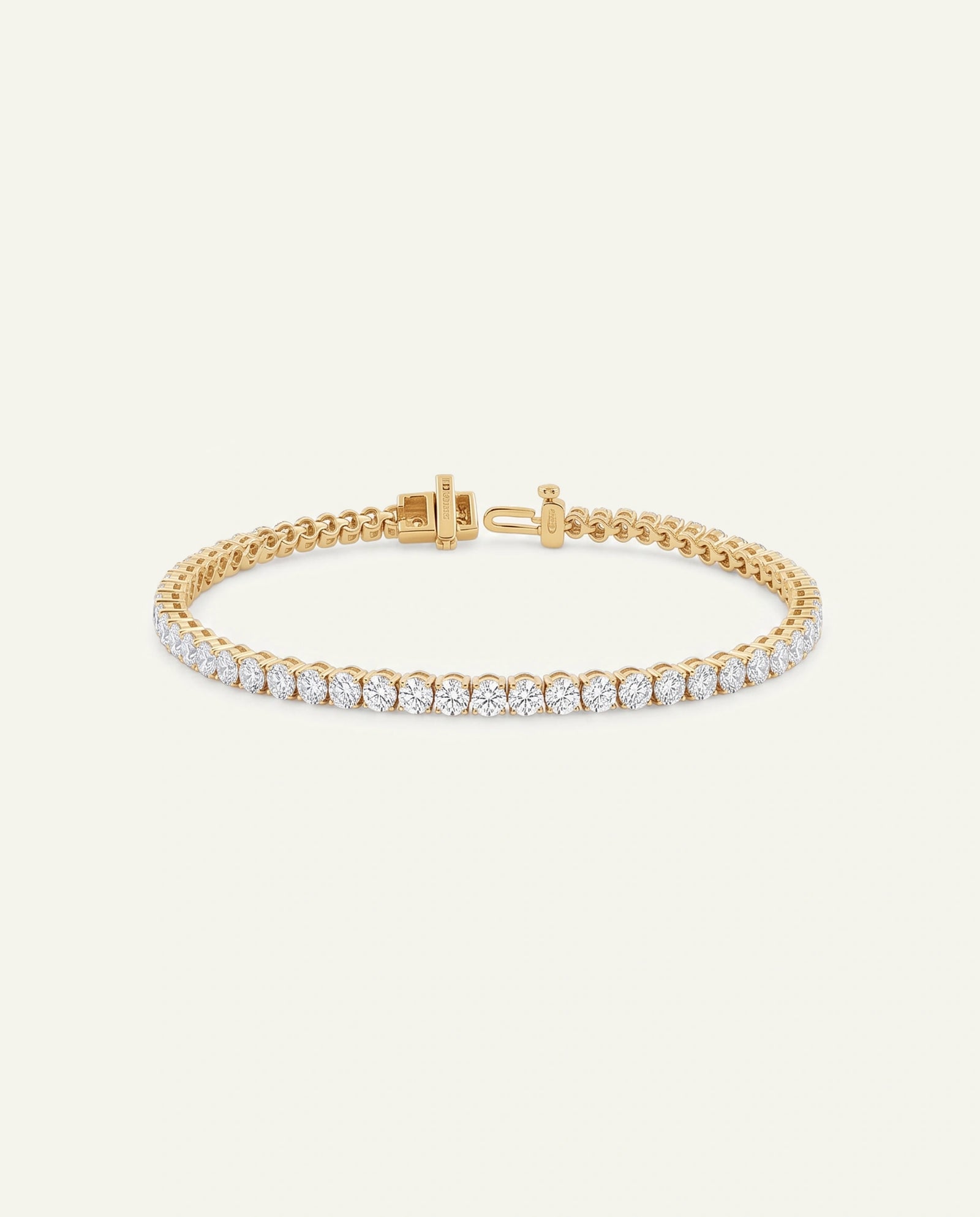 A gold tennis bracelet featuring a row of round-cut clear gemstones, displayed on a clean off-white background.