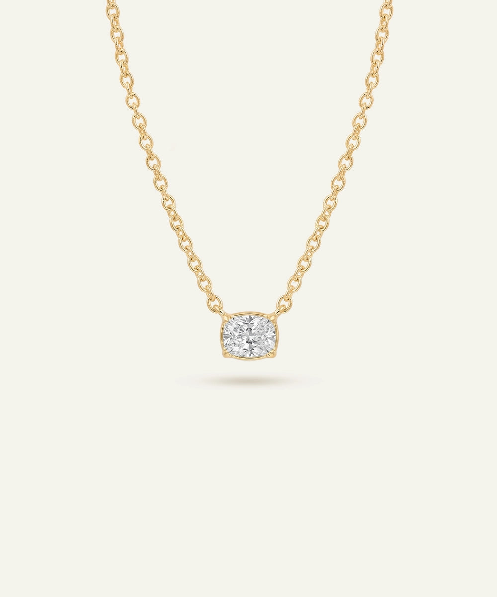 Gold necklace with a diamond pendant on a light beige background