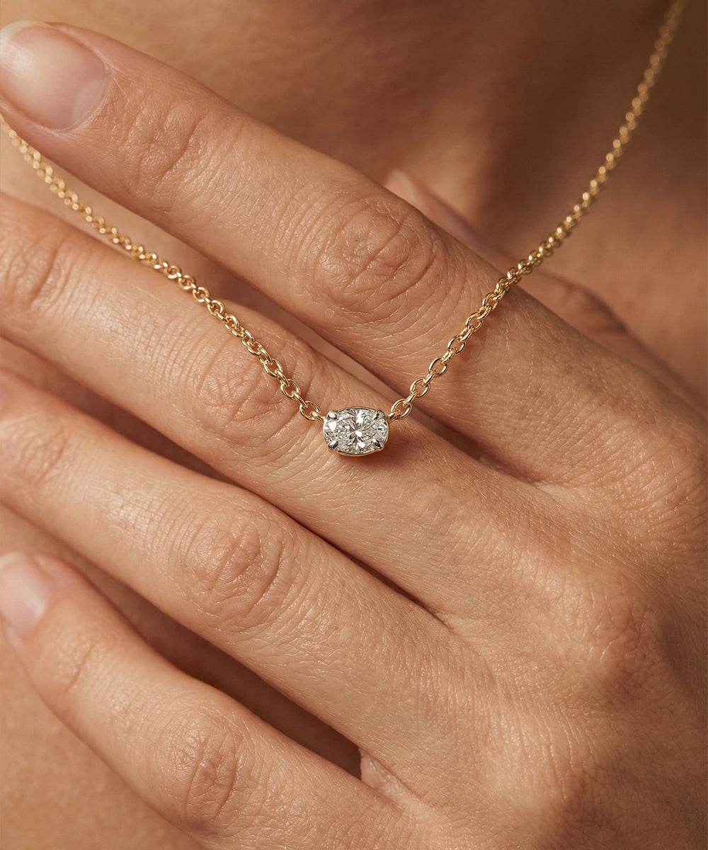 Gold necklace with a diamond pendant on a hand