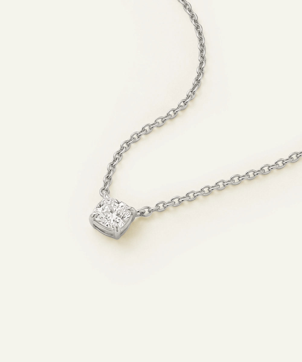 Heart-shaped diamond pendant on a chain against a white background
