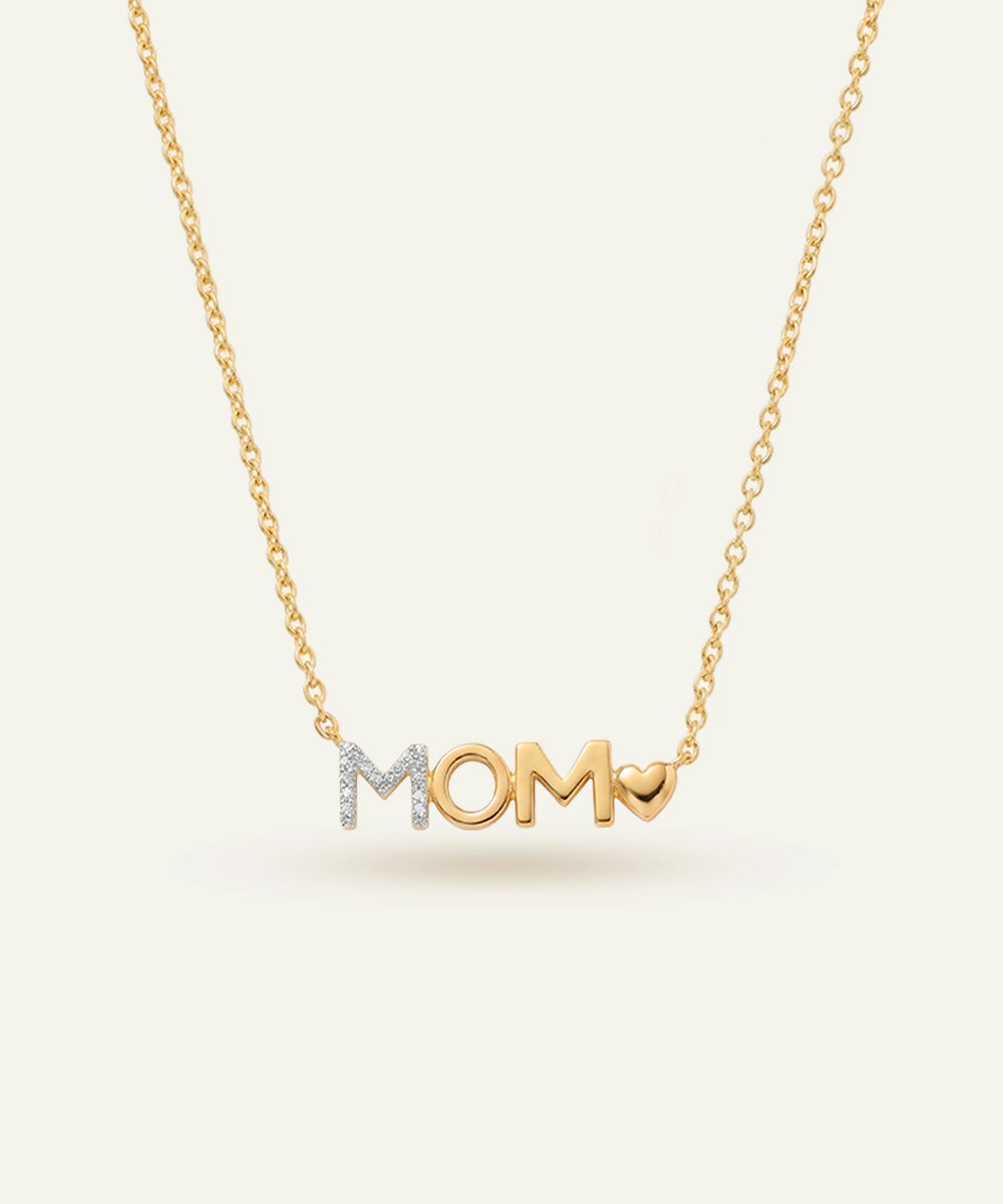 Gold necklace with 'MOM' pendant on a light beige background