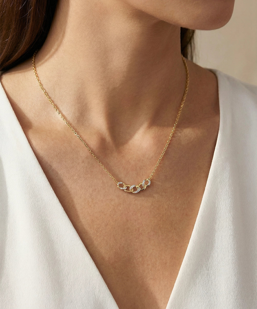 Gold necklace with a small pendant on a person wearing a white top.
