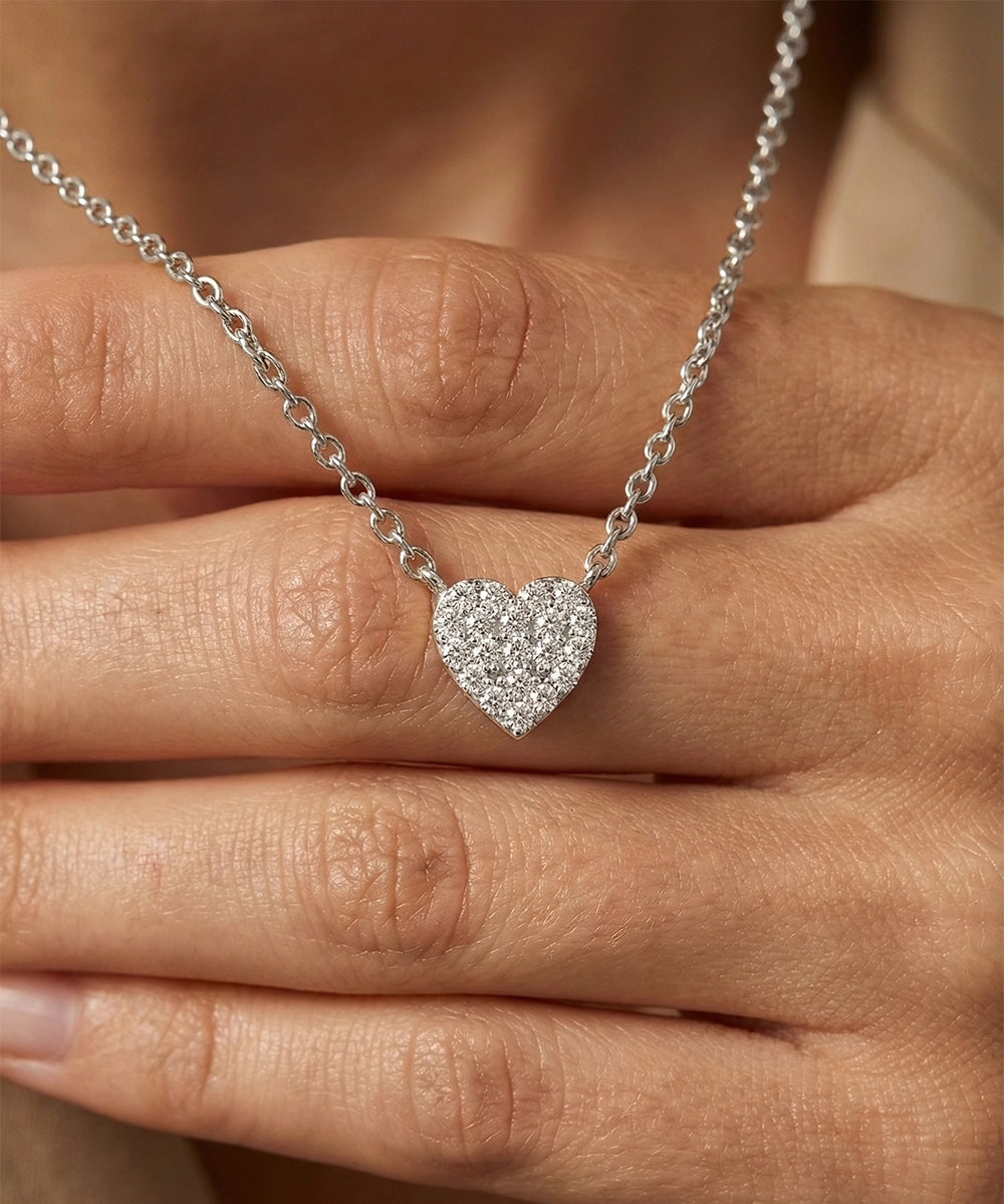Silver heart-shaped necklace held between fingers